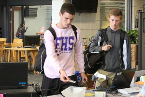 Mitch Chambliss (12) and Daniel Eberle(11) drop their ID's into the bin as they enter the library after school.