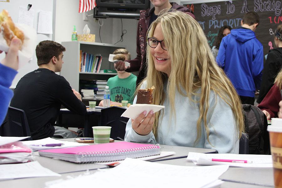 Sweet surprise starting off her day, Emma Krause (11) eats a donut in Stacey Bevills seventh hour Statistics class, March 3. The class won the donuts because of its 100 percent attendance for first hour on that Friday. “I was excited when we got donuts. It was a good surprise,” Krause said. “I have a sweet tooth, so donuts was just something nice.”
