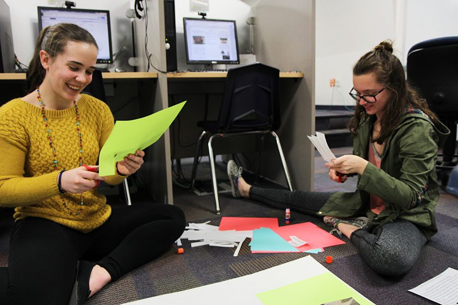 
Jamie Pack and Raegan Holland, Spanish 4 students, chat as they cut out paper for the poster they presented at the Poverty Awareness Fair in the library, March 8.