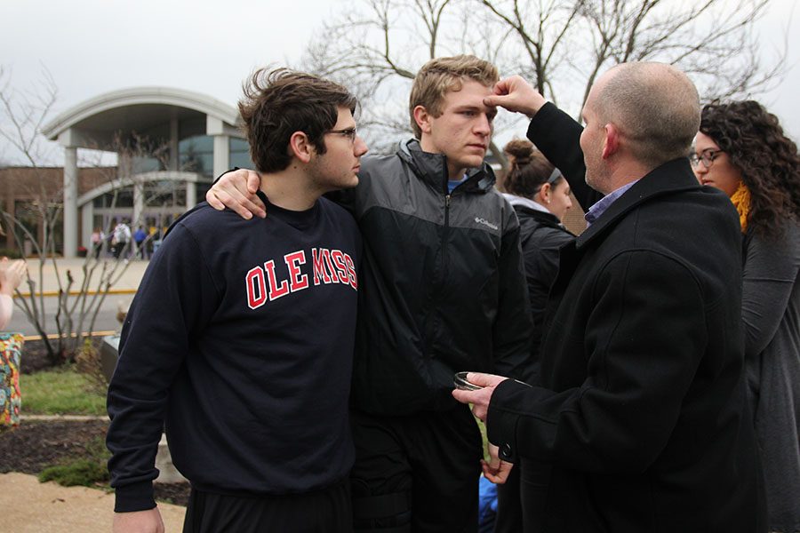 After hurting his knee in a soccer game, Ryan Giesing (12) had to lean on me to receive ashes from Pastor Tim Schulte at FCAs annual Ash Wednesday service at the flagpole, Mar.  1.  As we stand in front of the school weve called home, were reminded of the trials weve faced together in the past four years. I look up to this man-both literally and figuratively.