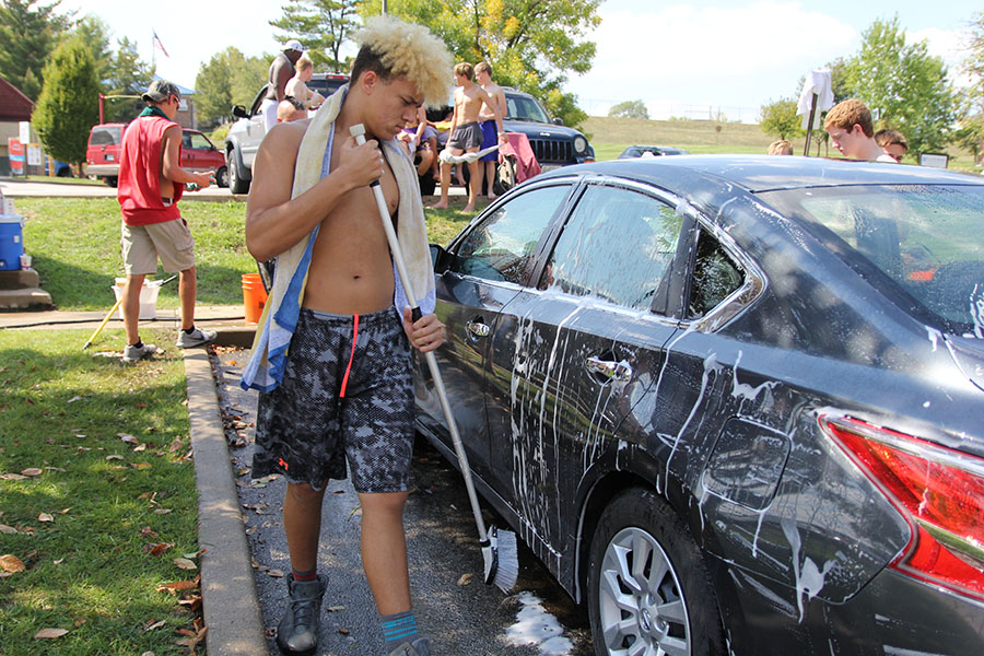 Tires receiving his attention, Harry Hill (10) scrubs down a car at Valvoline Instant Oil Change for the wrestling team’s car wash fundraiser, which was raising money for out-of-state competitions, Sept. 16. I got to hang out with all the team and meet a lot of the freshmen on a personal level,” Hill said. “It was team bonding for us. When we were trying to get people to come in with the signs, we still made it fun by dancing around and having fun. It was successful overall. We had more cars than last year. It was also cool to see the staff from school come out to support us.” The Wildcats raised $1,300 dollars. 