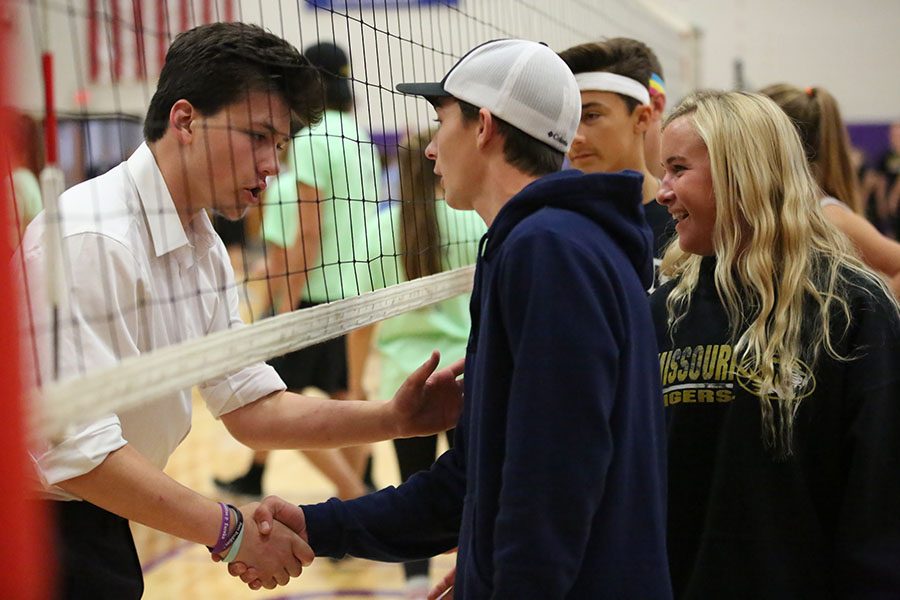 Complimenting their volleyball skills, Andy Mocker and Zach Walls (12) shake hands over a good game as teammates Jodi Mocker and Austin Kiefer (11) await their turns at the Puerto Rico Hurricane Relief Volleyball tournament, Oct. 27.