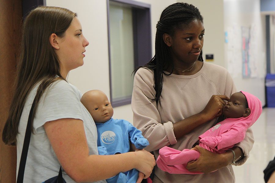Baby in their arms, Lydia Greenhagen and Coreyn Mason (11) take their practice babies around the school during Rachel Haywood’s sixth hour child development 2 class, Sept. 21. “I like the attention that everyone gives you when you have the fake baby,” Mason said. “Everyone rushes around you and says ‘Awh, they are so cute, let me see.’ It is fun. Mrs. Haywood keeps everything about the challenges of parenting real with us. She doesn’t sugarcoat anything and makes us think about what our parents went through and what those of us who want to be parents will go through. My favorite part is the people in the class. We all bonded really quick so we have genuine conversations and we aren’t afraid of being judged.”