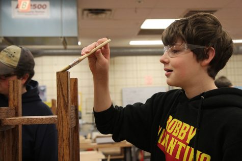 Table almost completed, Adam Fischer (9) adds lacquer to his table in Brad DeMattei’s Woods Process 1 class, Dec. 13. “I enjoy the machines. They can do things that we can’t,” Fischer said. “I took Woods all through middle school. It is a fun class to do. It is interesting being able to use your hands to make something of your own. It makes my school day better being able to come to this class and be creative. I’ve been working on the table the whole semester. I wanted to make it good because it is my mom’s Christmas gift.”